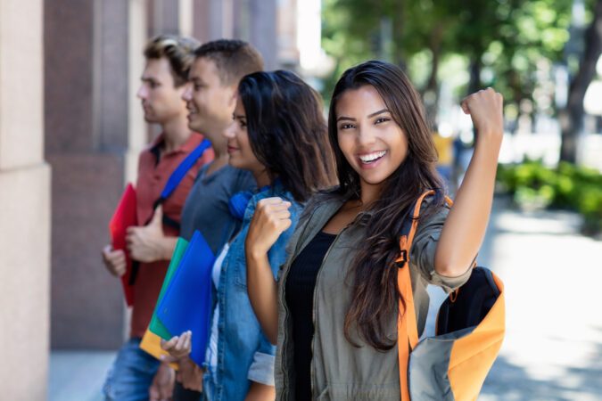 Successful cheering latin american female student with group of friends More money for School